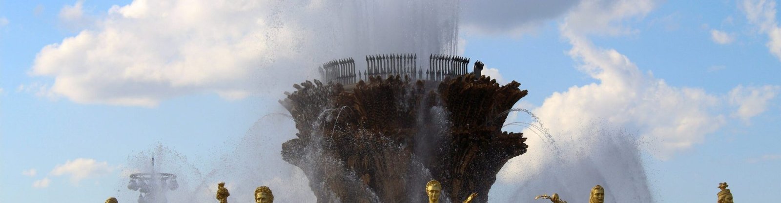 Stunning fountain with golden statues under a blue sky at VDNKh, showcasing artistic craftsmanship.